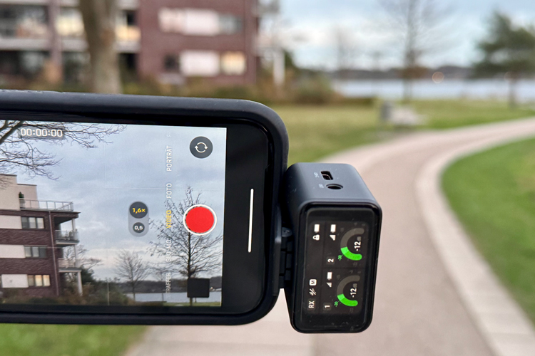 Display einer Videocam, im Hintergrund ist unscharf ein Wohngebäude und ein Gehweg in einer Parkatmosphäre zu sehen.