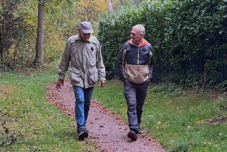 Hendrik Brunckhorst geht im Gespräch mit Uwe C. auf einem Gehweg in einem Park.